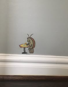 a small figurine is holding a pizza in it's mouth on the corner of a room