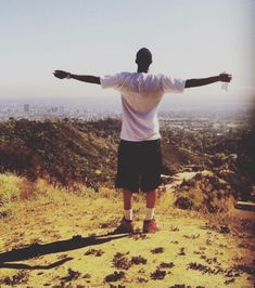 a man standing on top of a hill with his arms outstretched