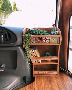 a wooden shelf with books and plants on it in the back of a vehicle's interior