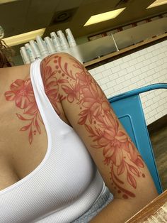 a woman with a flower tattoo on her arm and shoulder, sitting at a table