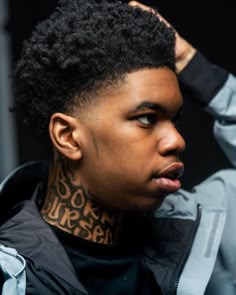 a young man with tattoos on his neck and shoulder is looking at the camera while wearing a jacket
