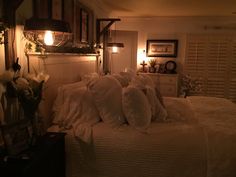 there is a bed with white sheets and pillows in the room that has lights on