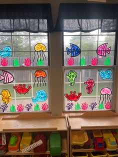 two windows with different colored fish and sea animals drawn on them
