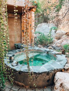 an outdoor hot tub surrounded by rocks and greenery