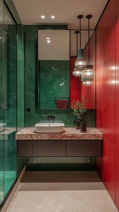 a bathroom with red and green walls, marble counter top and sink in the middle