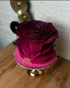 a pink rose sitting on top of a wooden table