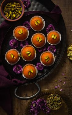 there are many cupcakes that have been decorated with nuts and flowers on the table