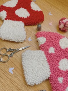 crocheted mitts and scissors are laying on the floor next to each other