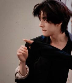 a woman holding up a black shirt in front of her face and pointing to the left