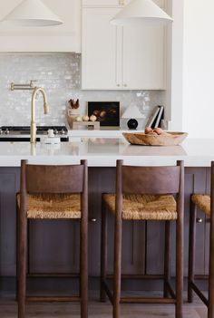 a kitchen with white cabinets and wooden stools in front of an island countertop