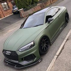 the green car is parked on the side of the road