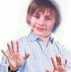 a young boy holding his hands up in the air