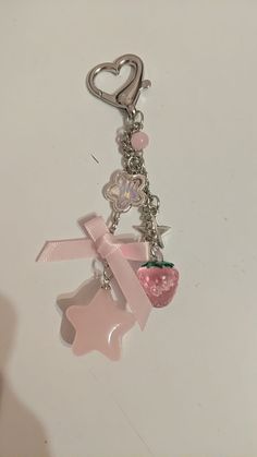 a key chain with charms attached to it on a white surface and a pink heart
