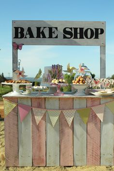 a wooden sign that says bake shop with bunting flags and desserts on it