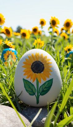 a painted rock with a sunflower on it sitting in the middle of a field