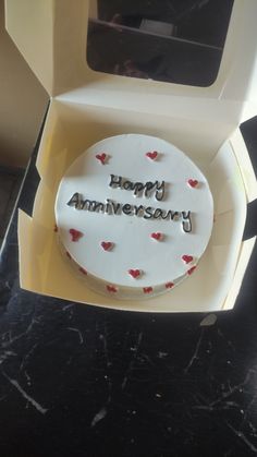 a birthday cake with the words happy anniversary on it sitting in a box next to a microwave