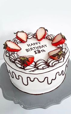 a birthday cake with strawberries on top and the words happy birthday written on it