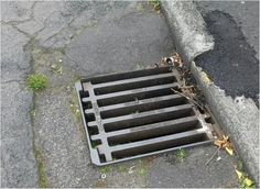 a drain grate sitting on the side of a road
