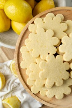 lemon cookies are arranged on a plate next to lemons