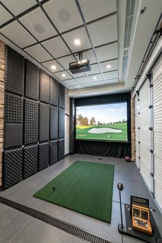an indoor golf simulator with green carpet and white walls