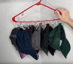 there is a red hanger with hats hanging from it's hooks on the wall