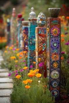 many colorful vases are lined up on the side of a road with flowers around them
