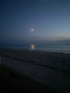 the moon is setting over the beach and ocean