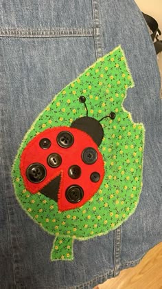 a ladybug patched onto the back of a jean jacket with buttons on it