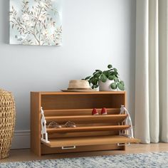 a wooden shelf with shoes on it in front of a white wall and a plant