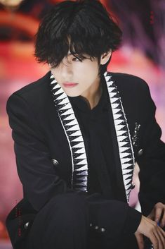 a man with black hair and white stripes on his jacket
