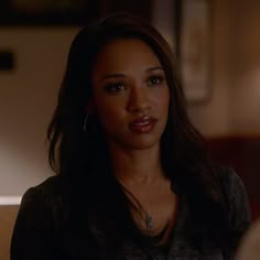 a close up of a person sitting down with a light in the back ground behind her