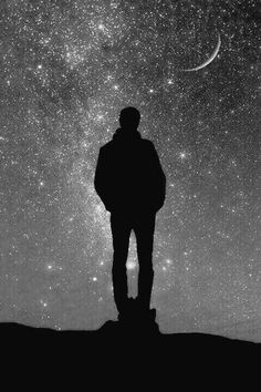 a man standing on top of a hill under the stars