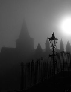 the sun shines through fog in front of an old building with spires on it