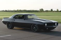 a black muscle car driving down the road
