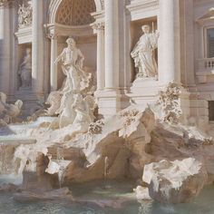 a fountain in front of a large building with statues on it's sides and water cascading