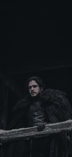 the man in black is standing on a ledge with his arms crossed and looking at something