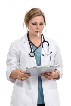 a woman doctor in white coat holding a clipboard and looking at it with a pen in her mouth