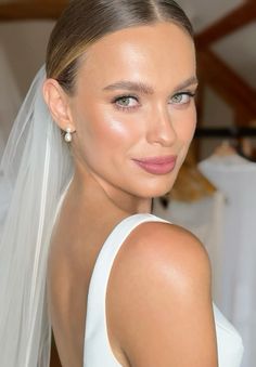 a woman wearing a white wedding dress with a veil on her head and pink lipstick