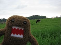 a brown stuffed animal with teeth on it's face standing in the middle of a grassy field