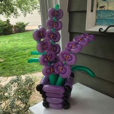 an inflatable vase with purple and green flowers sitting on a white table outside