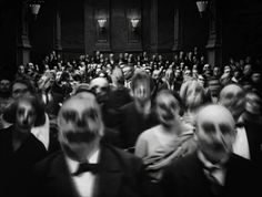 black and white photograph of people in front of an audience with their faces slightly obscured by masks