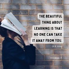 a woman with a book on her head is looking at the brick wall behind her