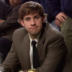 a man in a suit and tie sitting at a table with beer cans on it