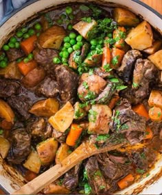 a pot filled with meat, potatoes and peas