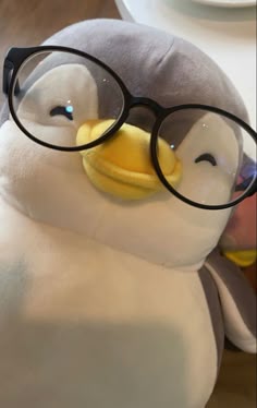 a stuffed penguin with glasses on it's face sitting next to a person wearing eyeglasses