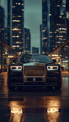 a rolls royce parked in front of a city at night