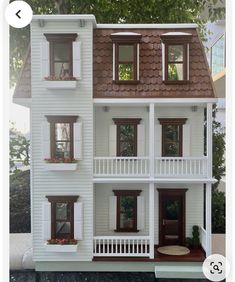 the doll house is white and has brown trim on the windows, doors, and balconies