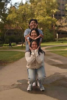 three people standing in the middle of a sidewalk with their hands on each other's heads