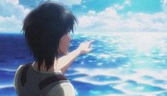 a person standing in front of the ocean with their hand up and pointing at something