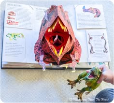 an origami frog is on the table next to a book